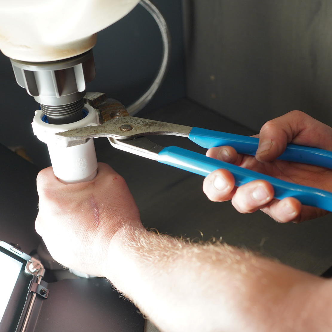 Plumber with pliers and sink